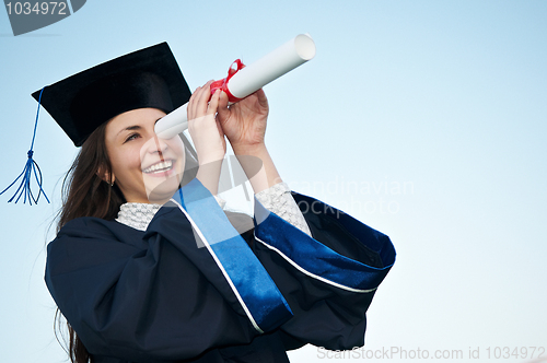 Image of happy graduate girl looking through diploma