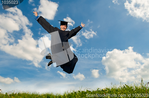 Image of happy jumping graduate outdoors