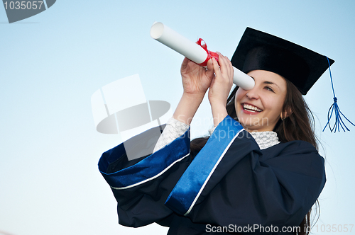 Image of happy graduate girl looking through diploma