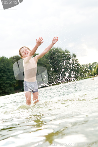 Image of happy boy in water with splashes