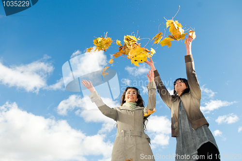 Image of Two girls and Autumn leaves over blue sky