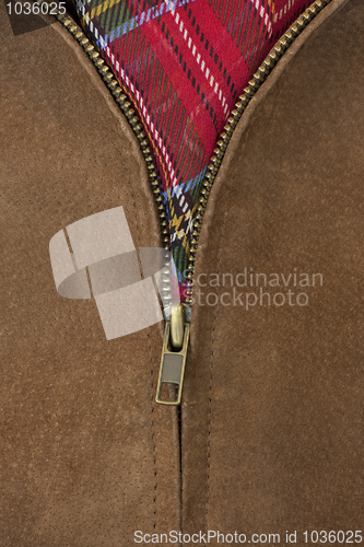 Image of unzipped brass zipper of leather jacket