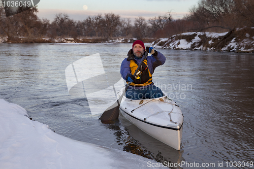 Image of paddling canoe on a winter river