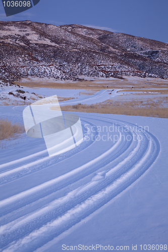 Image of windy country road covered by snow in mountain valley 