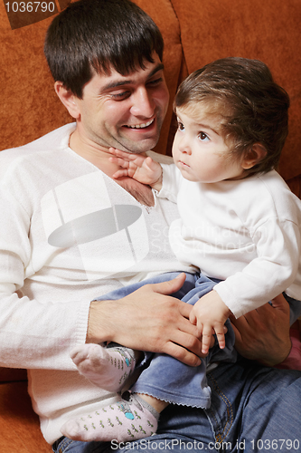 Image of Father sitting with little daughter on sofa