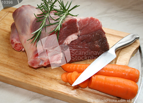 Image of A joint of lamb ready for cooking,with carrots and rosemary