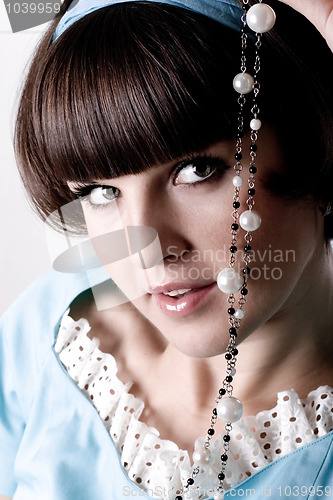 Image of brunette woman in blue dress with pearl beads