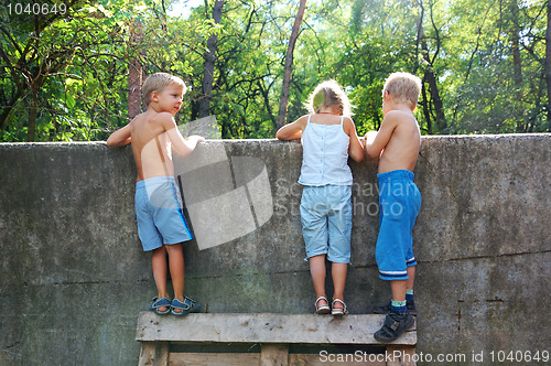 Image of curious children spying over the fence