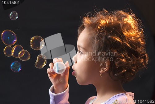 Image of little girl playing with soap bubbles 