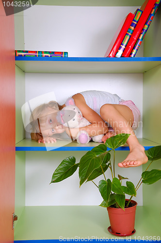Image of child in a bookcase with a toy