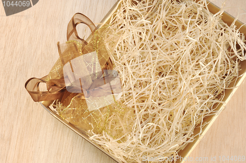 Image of Open gift box and bow - filled with packing bast