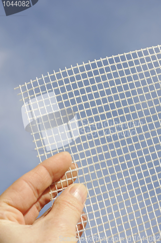 Image of Detail of glass-fiber mesh in hand – reinforcing material for insulation