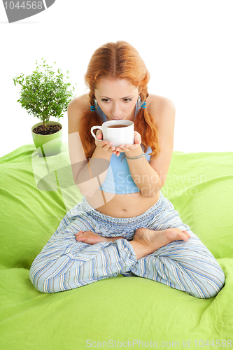 Image of Young woman in yoga pose drinking tea