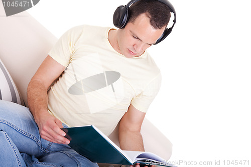 Image of man reading and listening music with headphones on couch