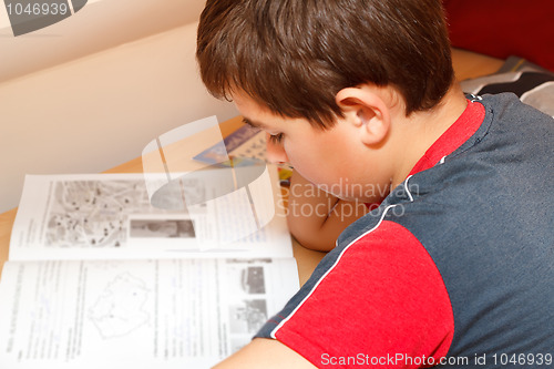 Image of boy doing homework, reading text from workbook