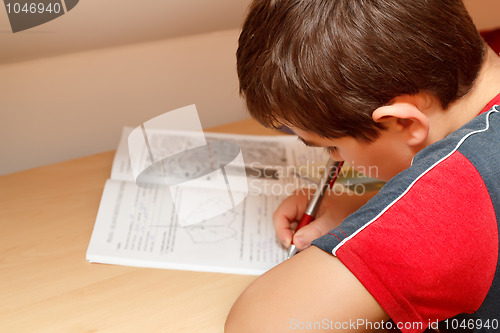 Image of boy doing homework, writing text from workbook