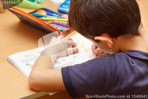 Image of boy doing homework  with color pencil, painting fruits