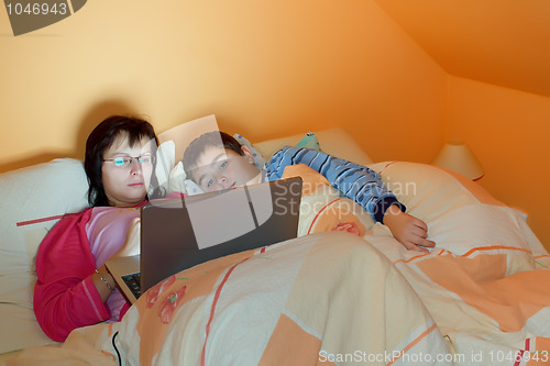 Image of Portrait of a mother and her son using laptop while lying on the bed at home 