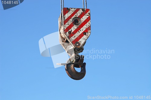 Image of rusty crane hook and steel cables hanging on blue sky