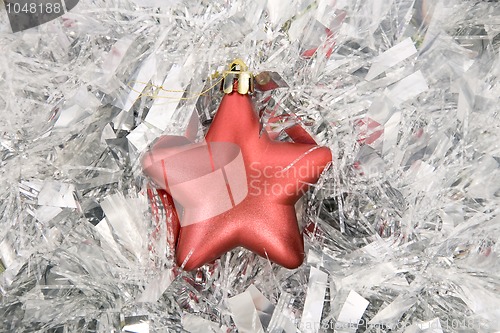 Image of red star, christmas decoration on silver tinsel