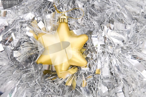 Image of golden star, christmas decoration on silver tinsel