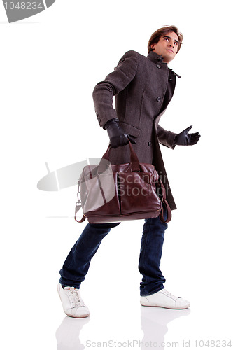 Image of Portrait of a young man with a handbag, hasty, in autumn/winter clothes