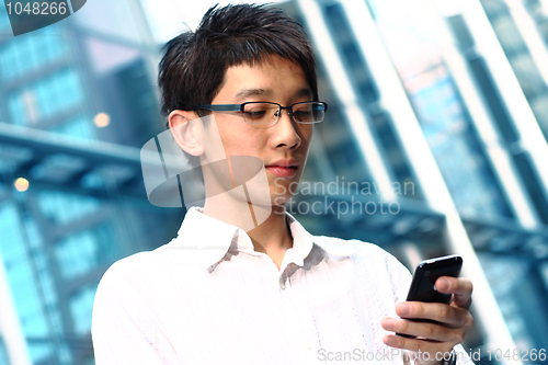 Image of casual asian businessman texting on his cell phone