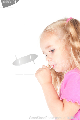 Image of Little cute girl in studio eating candy