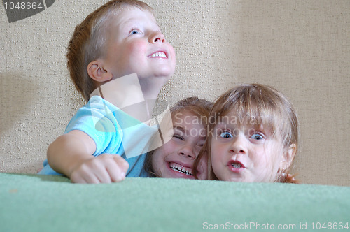 Image of happy children hiding behind the sofa