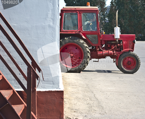 Image of red tractor resting in a white wall