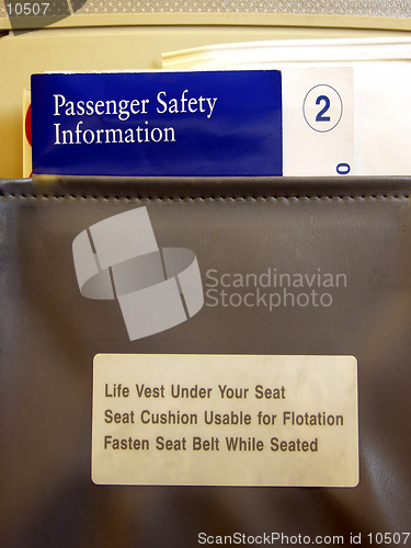 Image of Inside a commercial airliner.  Shows the Safety Information brochures and barf bag in the seat pocket behind the airline seat in front of you.