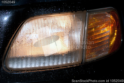 Image of headlight by rain with water splash