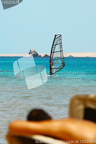 Image of Man tans on windsurfing background