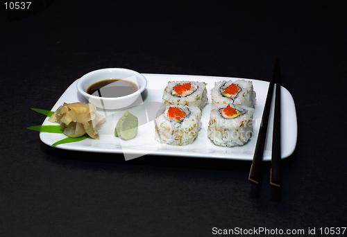 Image of A California Roll (sushi) sliced on a dish with soy sauce, ginger, wasabi, and chopsticks.(14MP camera)