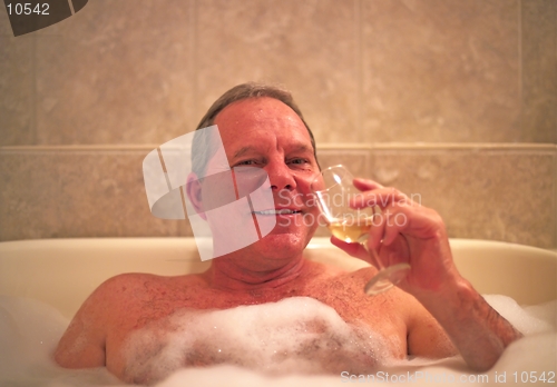 Image of A man with a glass of wine enjoys his relaxing jacuzzi bath in a resort hotel. Model released. (14MP camera)