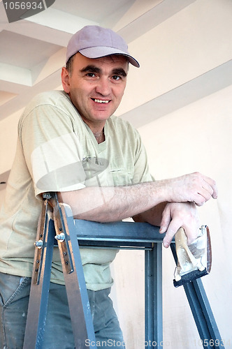 Image of builder on a ladder with a tool