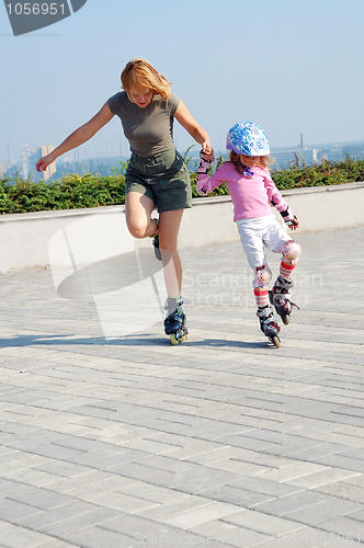 Image of mother teaching daughter rollerblading