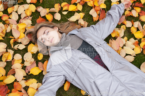 Image of Beautiful girl rests upon autumn sheet