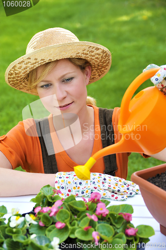 Image of Young woman watering flowers