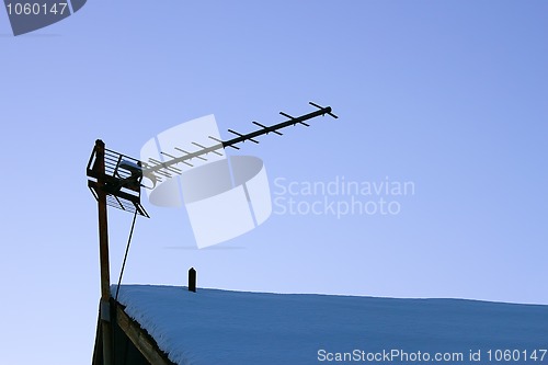 Image of Television antenna over the snowy roof 