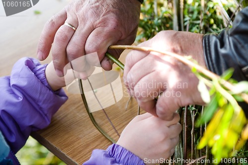 Image of Man teaching child making a wicker basket