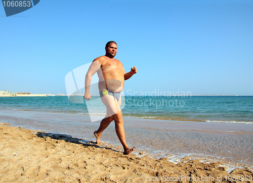 Image of overweight man running on beach