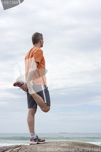 Image of Mature runner doing exercises at a beach