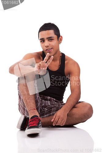 Image of Young latin man, sitting on floor, with thumb raised as a sign of victory