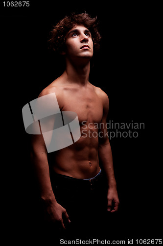 Image of young man in topless looking up to the light - sign of believe