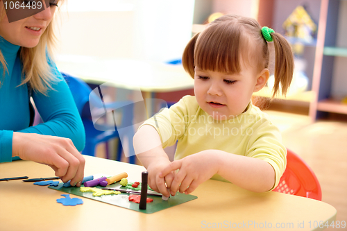 Image of Teacher and little girl play with plasticine