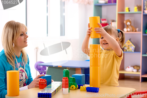 Image of Teacher and preschooler play with building bricks