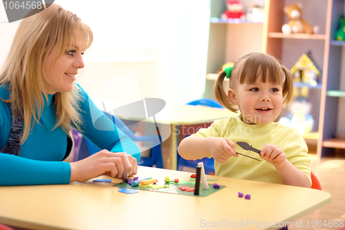 Image of Teacher and little girl play with plasticine