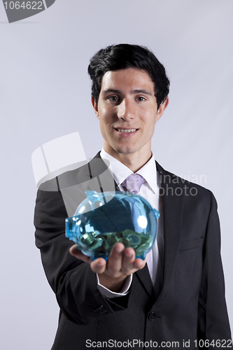 Image of Businessman holding a piggybank full of coins