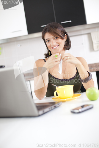 Image of Modern woman reading e-mails at her breakfast